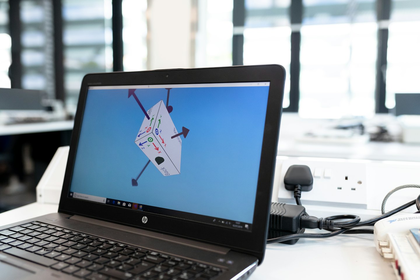 Laptop z wizualizacją 3D na białym biurku.